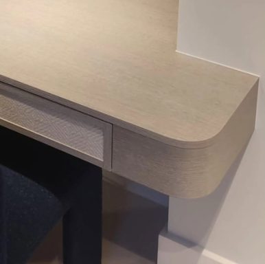 Small fitted Desk. Close-up of a light-coloured wooden desk corner with a small drawer.